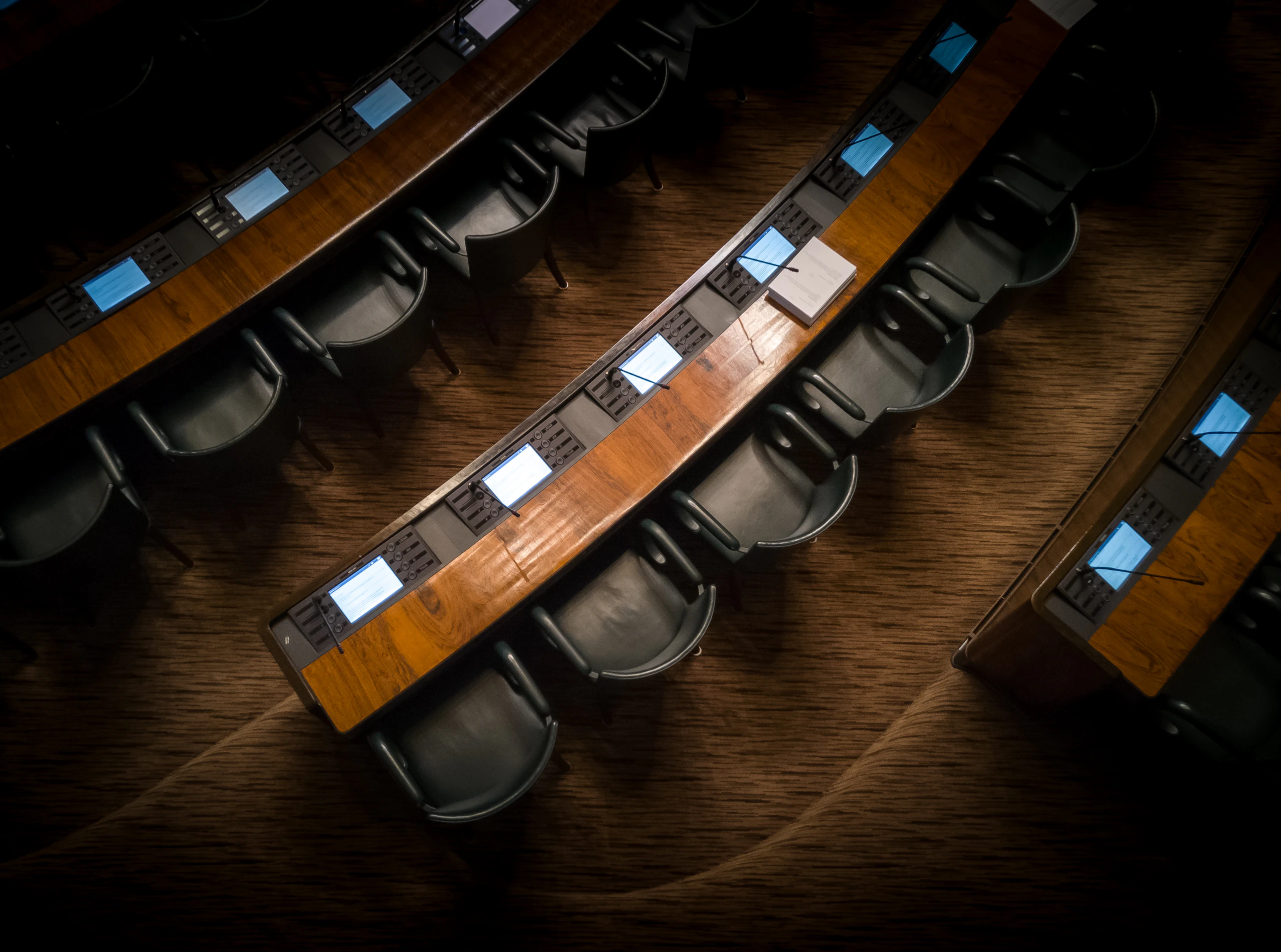 An empty council chamber, desks curved around a floor